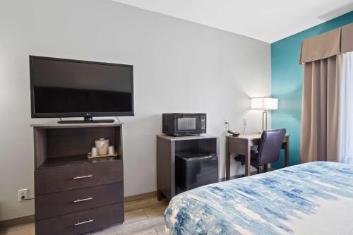a hotel room with a bed and a flat screen tv at Blue Water Inn & Suites BW Signature Collection in North Topsail Beach