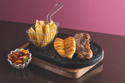a tray with meat and chips and a bowl of vegetables at Hotel Tungurahua in Baños