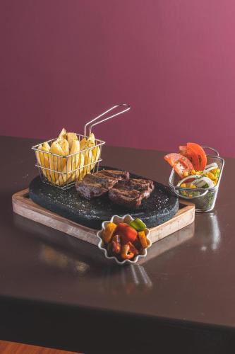 a grill with meat and vegetables and a basket of food at Hotel Tungurahua in Baños