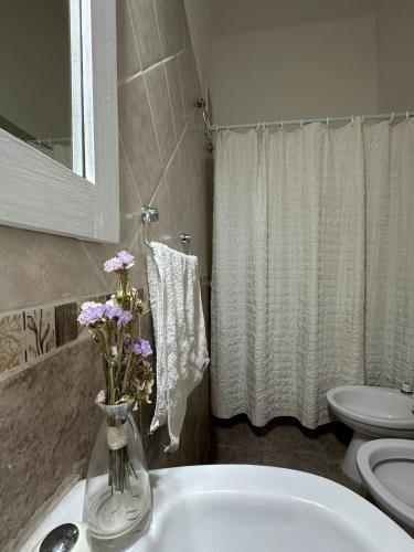 a bathroom with a sink and a vase with flowers in it at AMPLIOS Departamentos PASAJE TUCUMÁN in Alta Gracia