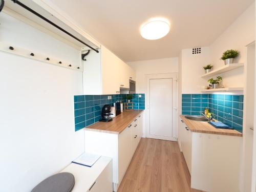a kitchen with white cabinets and blue tile at ApartManó in Balatonfüred