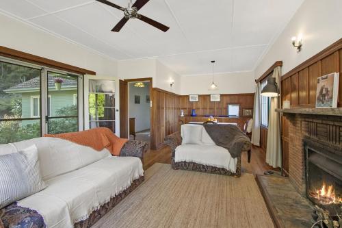 un soggiorno con divano bianco e camino di Gowan Ross Cottage a Mount Wilson