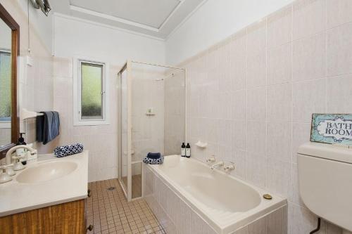 un bagno bianco con vasca e lavandino di Gowan Ross Cottage a Mount Wilson