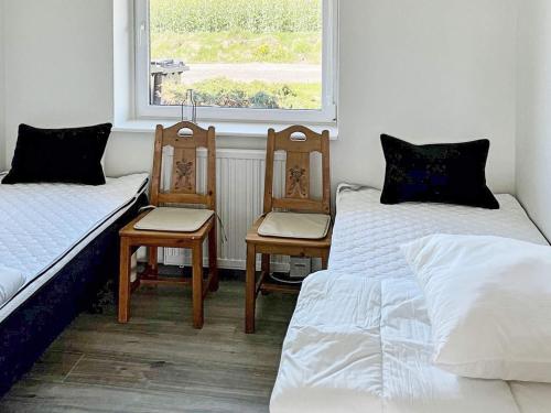 a room with two beds and two chairs and a window at Holiday home Østervrå II in Østervrå