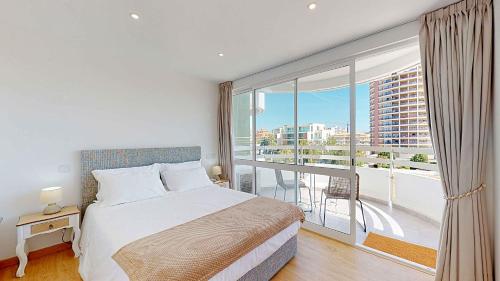 a bedroom with a bed and a large window at Apartamento da Avó Té - em frente à Praia c piscina in Portimão