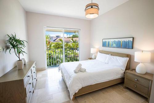 una camera da letto bianca con un letto e una finestra di Modern Apartment - Steps to Puntarena Beach Club & Shops - Marina Overlook - Sleeps 10 a Boca de Río Hato