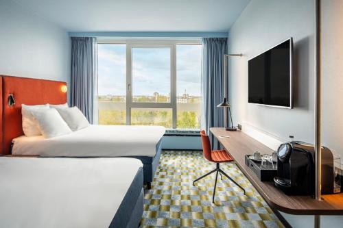 a hotel room with two beds and a desk and a tv at Crowne Plaza Antwerpen by IHG in Antwerp