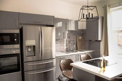 a kitchen with a refrigerator and a counter with chairs at Modern 4 Bed En-suite House in Leeds - Free parking in Headingley