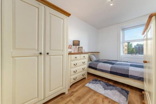 ein Schlafzimmer mit einem Bett, einer Kommode und einem Fenster in der Unterkunft One bedroom flat in Central London #02 in London