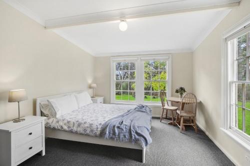 a bedroom with a bed and a desk and windows at The Teachers Cottage in Mount Wilson