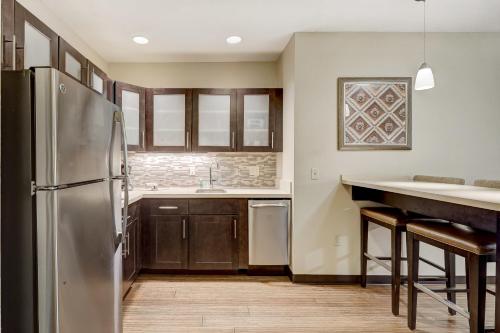 a kitchen with a stainless steel refrigerator and wooden cabinets at Staybridge Suites Baltimore - Inner Harbor by IHG in Baltimore