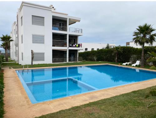 une maison avec une piscine en face d'un bâtiment dans l'établissement Résidence Galets Sur Mer, à Dar Bouazza