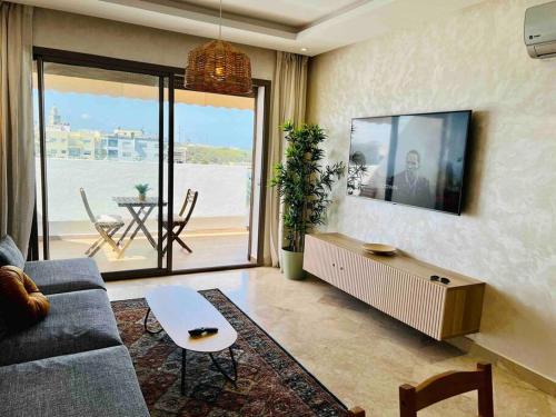ein Wohnzimmer mit Couch und Fernseher in der Unterkunft DreamParc - Vue sur Mer et Parc Securite 24H in Mohammedia