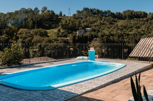 a blue swimming pool in a yard with a fence at Casa da bela Vista in Gramado