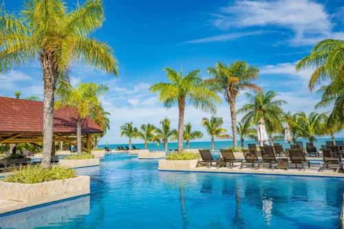 een zwembad van het resort met stoelen en palmbomen bij Steps to Puntarena Beach Club and Restaurants - Amazing Location - Sleeps 9 in Boca de Río Hato