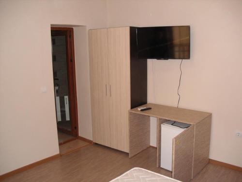 a room with a desk and a television on a wall at Family Hotel Malibu in Chernomorets