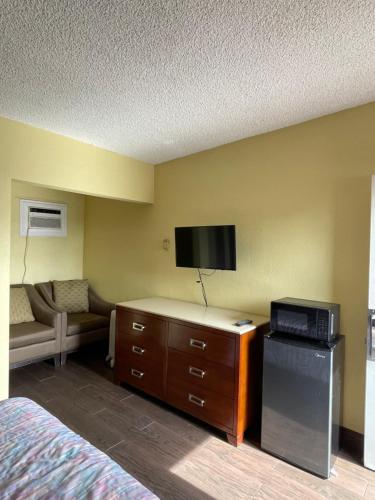 a hotel room with a bed and a flat screen tv at Rancho Motel - Ontario Airport in Ontario