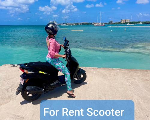 a young girl sitting on a scooter on the beach at The Santy's in Oranjestad