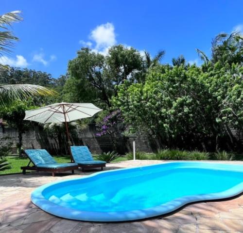 a swimming pool with two chairs and an umbrella at Recanto Vieira Praia do Estaleiro in Balneário Camboriú