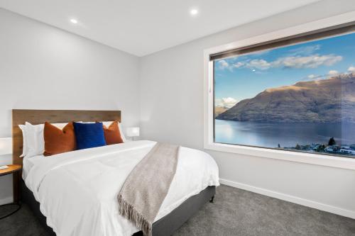 Schlafzimmer mit einem großen Fenster und einem Bett in der Unterkunft Rivendell, Luxury Cliff Top Home, Queenstown - Spa & Sauna in Queenstown