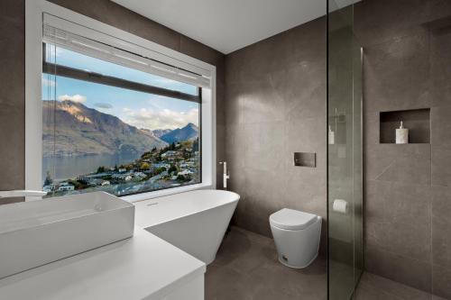 ein Badezimmer mit einem großen Fenster und einer weißen Badewanne in der Unterkunft Rivendell, Luxury Cliff Top Home, Queenstown - Spa & Sauna in Queenstown