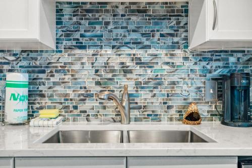 a kitchen with a sink and a blue tiled wall at Sea-Renity at Laketown Wharf #1607 by Nautical Properties in Panama City Beach