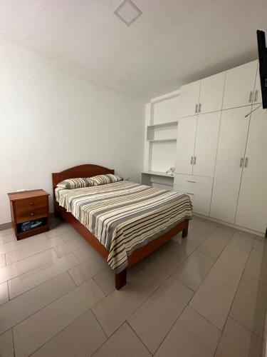 a bedroom with a bed and a dresser and white cabinets at Alojamiento increíble!! in Iquitos