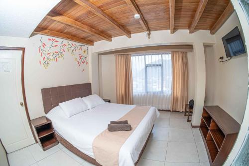 a bedroom with a large bed and a television at Hotel Tungurahua in Baños