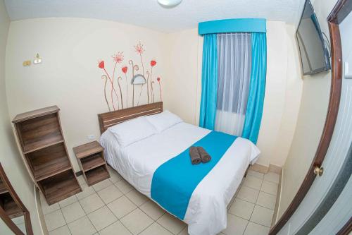 a small bedroom with a bed with blue curtains at Hotel Tungurahua in Baños