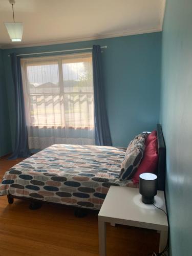 1 dormitorio con cama, ventana y mesa en Corio (Geelong) Holiday Villa, en Corio