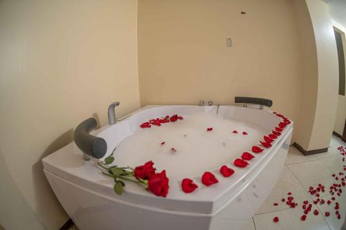 eine weiße Badewanne mit roten Rosen darauf in der Unterkunft Hotel Tungurahua in Baños
