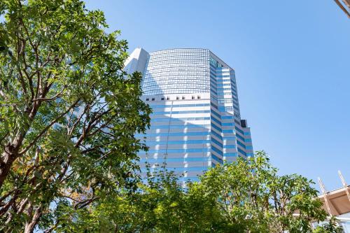 ein hohes Glasgebäude mit Bäumen davor in der Unterkunft The Strings by InterContinental, Tokyo, an IHG Hotel in Tokio