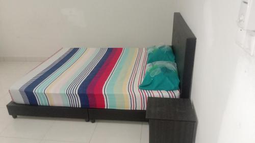 - un lit avec une couette rayée colorée dans l'établissement Hillpark Residens, à Semenyih