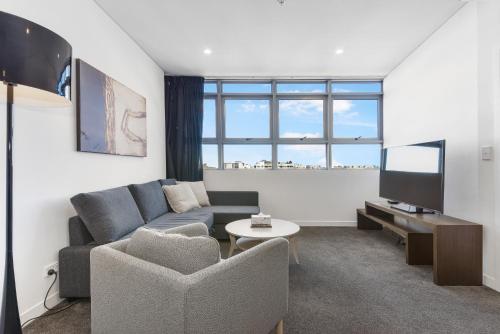 a living room with a couch and a tv at Broad Land Premium Apartments Chatswood Sydney in Sydney
