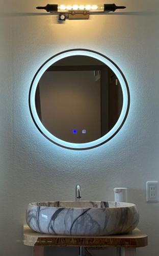 a bathroom sink with a round mirror on the wall at Japow House 2 on Main Street in Myoko