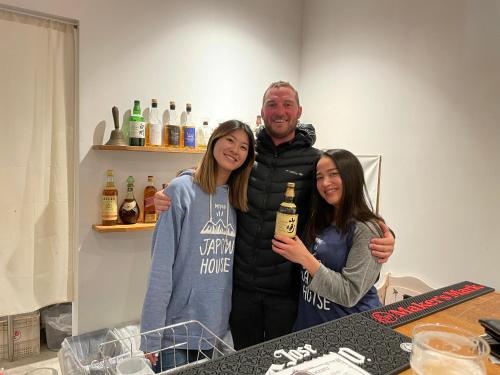 a man and two women holding a bottle of wine at Japow House 2 on Main Street in Myoko