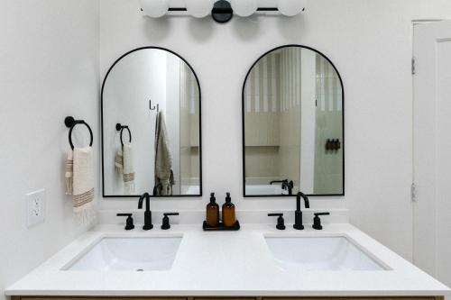 a bathroom with two sinks and two mirrors at Yara Hotel - Adults Only in Palm Springs