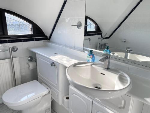 a white bathroom with a sink and a toilet at Riverside 4 Bedroom House Wraysbury Staines in Wraysbury