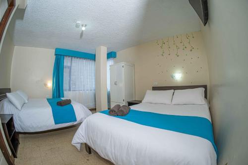 a bedroom with two beds with blue and white at Hotel Tungurahua in Baños