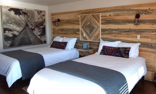 two beds in a hotel room with wooden walls at Horseshoe Bend Motel in Lovell