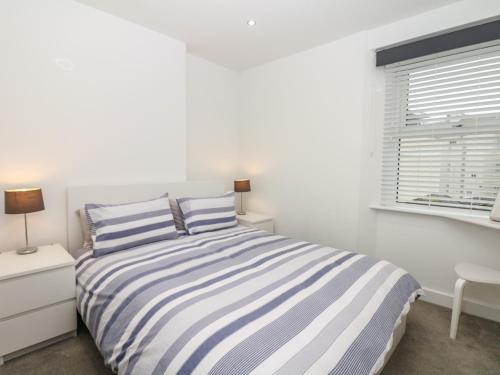 una camera bianca con un letto a righe e una finestra di Sea Aster a Teignmouth