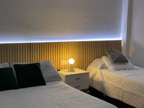 1 dormitorio con 2 camas y mesita de noche con lámpara en Iluminada Haus en Buenos Aires