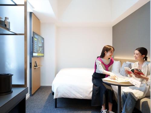 two women sitting at a table in a hotel room at CROSS Life Hakata Yanagibashi in Fukuoka