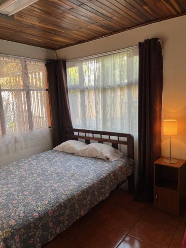 um quarto com uma cama e duas janelas em El mochilero em Cartago