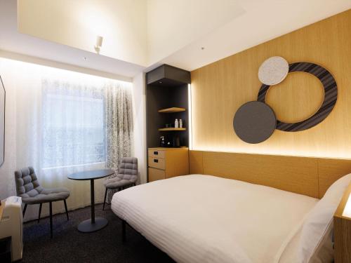 a bedroom with a bed and a table and chairs at CROSS Life Hakata Yanagibashi in Fukuoka