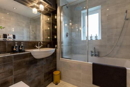uma casa de banho com uma banheira, um lavatório e um chuveiro em iStay Here Ltd - 1 Bed House with Wifi and Parking - An African Adventure em Aston End
