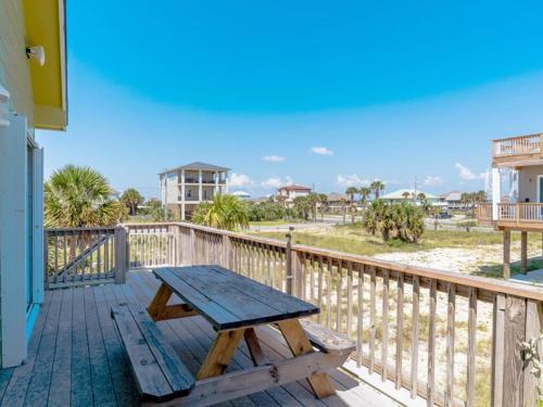 a wooden deck with a picnic table on a balcony at Lazy Urchin Seaclusion in Pensacola Beach
