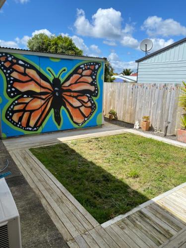een vlindermuurschildering aan de zijkant van een hek bij Home away from home air b and b in Whangarei