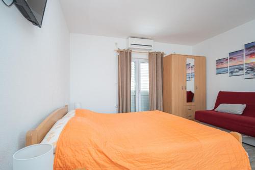 1 dormitorio con cama naranja y sofá rojo en Apartments by the sea Tkon, Pasman - 17360, en Tkon