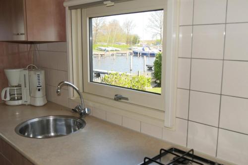 um balcão de cozinha com um lavatório e uma janela em VVP Verhuur Chalet Vinkeveense Plassen em Vinkeveen